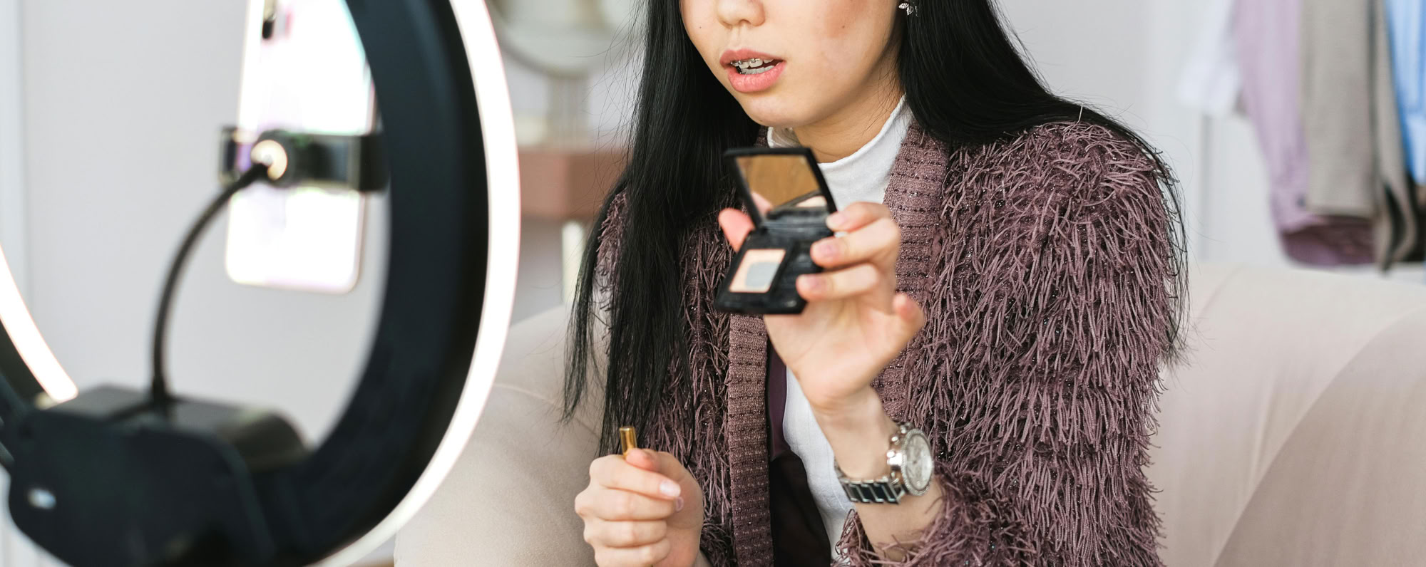 Young woman recording a makeup tutorial with a ring light for her vlog.